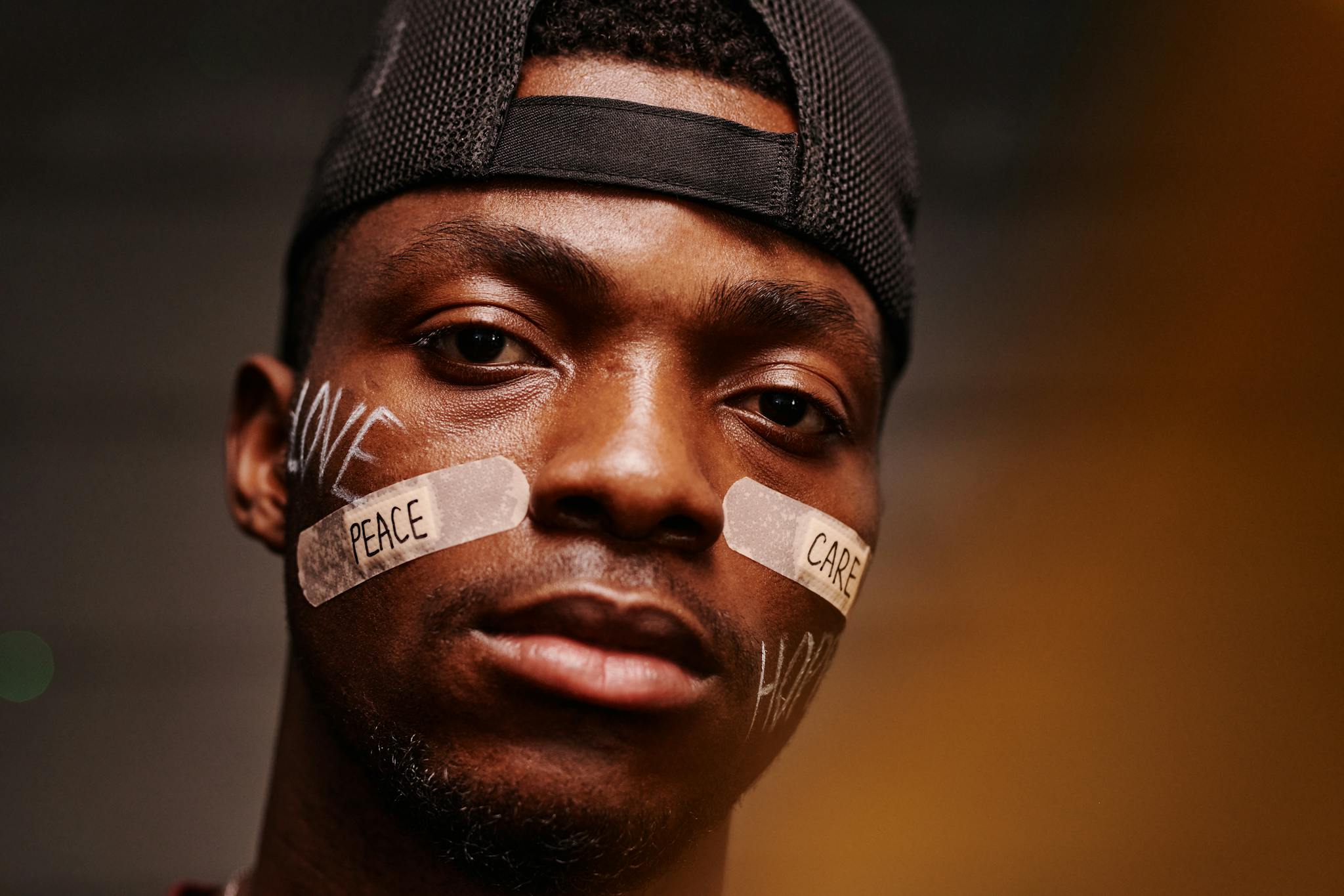 Close-up portrait of a man with band aids displaying 'peace' and 'care' messages.